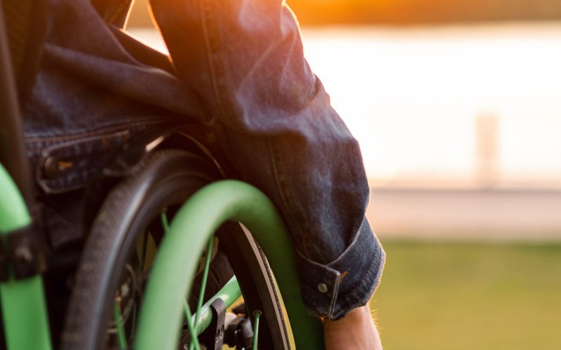 A disabled man is sitting in a wheelchair. He holds his hands on the wheel. High quality photo